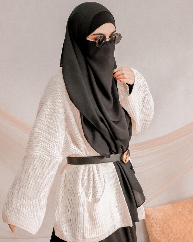 Selain warna pastel, Wawa juga memilih tampilan preppy look bernuansa monokrom. Ia memadukan knit wear cardigan, dress dengan belt  hitam. Dan menambahkan aksesori kaca mata hitam yang membuat penampilannya tetap stylish saat memakai niqab. Foto: Dok.Instagram @wardahmaulina_.