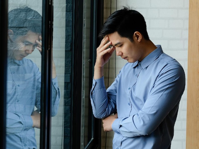 1044024846 Business man Feeling exhausted massaging headache and stand at his working place in office.