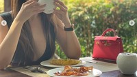 Helena yang hobi koleksi tas mewah ini tampak asyik menyeruput secangkir teh. Tas mungil berwarna merah menamani momen sarapannya.  Foto: @helenalim889