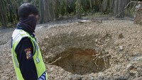 Seorang petugas sekuriti memperhatikan lubang semburan gas bercampur lumpur di Pondok Pesantren Al-Ihsan, Kota Pekanbaru, Riau, Sabtu (13/2/2021).