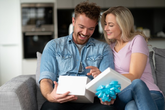 1187250858 Portrait of a very happy man opening a gift from his girlfriend at home and smiling - anniversary concepts