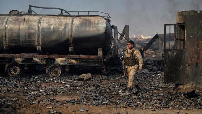 A security forces personnel walks amidst wreckage of gas tankers after a fire accident at Islam Qala on the outskirts of Herat, in the border between Afghanistan and Iran on February 14, 2021. (Photo by HOSHANG HASHIMI / AFP)