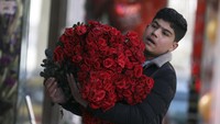 Seorang pria membawa buket bunga berukuran cukup besar saat perayaan hari kasih sayang di Kabul, Afghanistan, Minggu (14/2/2021). AP Photo/Rahmat Gul.