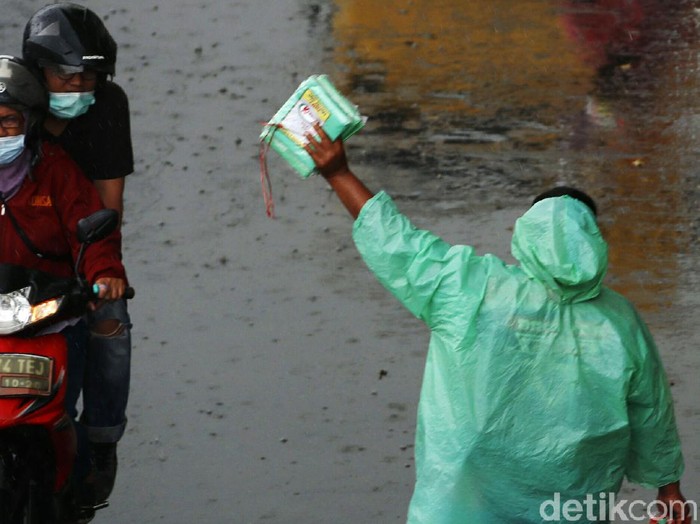 Hujan deras yang mengguyur wilayah Jakarta dan sekitarnya menjadi berkah bagi penjual jas hujan. Dagangannya laris dibeli pengendara sepeda motor.