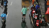 Penjual menawarkan jas hujan kepada pengendara motor yang melintas di Jalan Abdullah Syafei, Kampung Melayu, Jakarta.