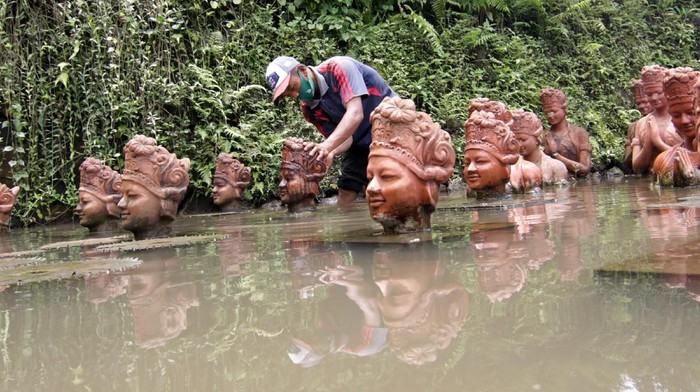 Pekerja membersihkan patung penari gandrung di Terakota Banyuwangi, Jawa Timur, Senin (15/2/2021). Pembersihan patung yang menjadi ikon Kabupaten  Banyuwangi itu sebagai perawatan setelah sebelumnya terpapar abu vulkanik dampak erupsi Gunung Raung. ANTARA FOTO/Budi Candra Setya/hp.