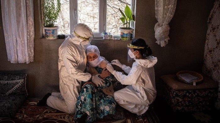 Potret Perjuangan Tim Medis Vaksinasi ke Pedalaman Turki VAN, TURKEY - FEBRUARY 11: Nurse, Bilge Koc and nurse, Gokalp Balli of the Gevas Public Health Center vaccination team, prepare to vaccinate 81 year old Selim Saypak with the Chinese Sinovac Coronavac vaccine during a house call in the village of Ikizler on February 11, 2021 in Van, Turkey. Since shipments of the Chinese Sinovac Coronavac vaccine arrived in Turkey on December 30, 2020, medical teams across the country have been working house to house to administer the COVID-19 vaccine to elderly and vulnerable citizens. For the members of the Van City, Gevas Province Public Health Centre vaccination teams, who specialise in remote locations, often high in the mountains or villages that have become inaccessible by car, due to heavy snowfall and road closures, house calls pose many unique challenges. The teams are often forced to hand carry the vaccine for kilometres through deep snow and mud to gain access to the village and administer the vaccine. Since the start of the vaccine campaign in Turkey the two specialist mobile teams have vaccinated more than 130 citizens in rural villages, some as old as 106. Turkeys official drug and medical equipment body approved the Chinese Sinovac Coronavac vaccine for emergency use against the novel coronavirus on the 13th of January 2020. According to data from Turkey’s Health Ministry the country has vaccinated more than 3.6 million people. The death toll from the coronavirus in Turkey has reached more than 27,000 and the number of infections has topped 2.5 million since mid-March 2020. Globally more than 107 million people have been infected by the virus. (Photo by Chris McGrath/Getty Images)