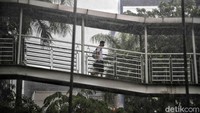 Seorang warga melintas di JPO saat hujan mengguyur kawasan Sunter, Jakarta Utara.