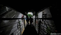 Sejumlah warga berteduh di JPO saat hujan mengguyur kawasan Sunter. Hingga kini JPO dan kolong jembatan masih jadi jujugan warga untuk berteduh saat hujan.