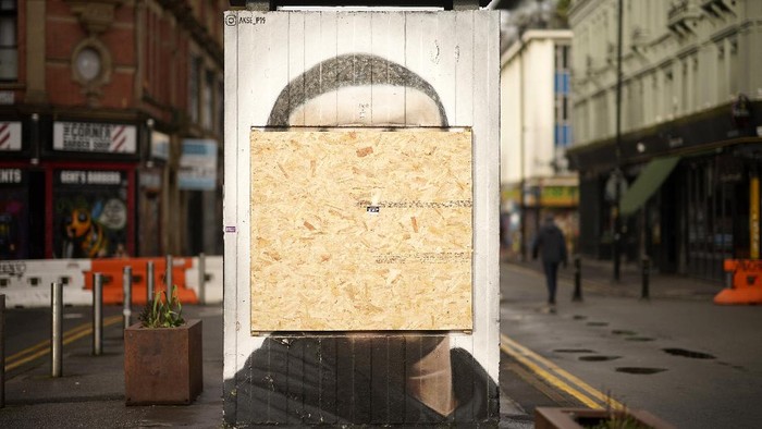Mural George Floyd Dirusak dan Ditutup Papan Kayu MANCHESTER, ENGLAND - FEBRUARY 15: A wooden board covers the George Floyd memorial mural on Stevenson Square after it was defaced with racist graffiti on February 15, 2021 in Manchester, England. The mural showing George Floyd, whose death in police custody in the United States ignited a wave of Black Lives Matter protests there and in Europe, was targeted by vandals for a second time. The mural creator, artist Akse has been commissioned to repair it once again. (Photo by Christopher Furlong/Getty Images)
