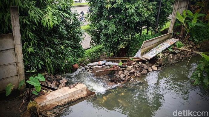 Warga melintas di tali air atau saluran air yang jebol sepanjang 3 meter di RT 03 RW 04, Parigi, Pondok Aren, Tangerang Selatan, Rabu (17/2/2021).