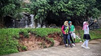 Beberapa warga justru menjadikan aliran air yang mengalir dari tanggul jebol sebagai background untuk swafoto.