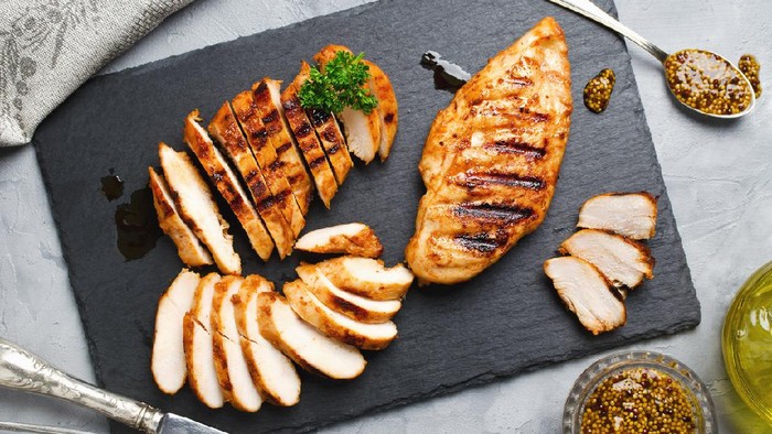 Grilled chicken fillets on slate plate. Gray concrete background