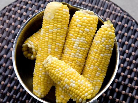 Closeup image of a woman holding and showing sweet corn