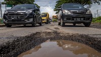 Sejumlah kendaraan melintas di jalan berlubang jalur Pantura, Jalan Raya Sayung, Demak, Jawa Tengah, Rabu, (17/2/2021). 