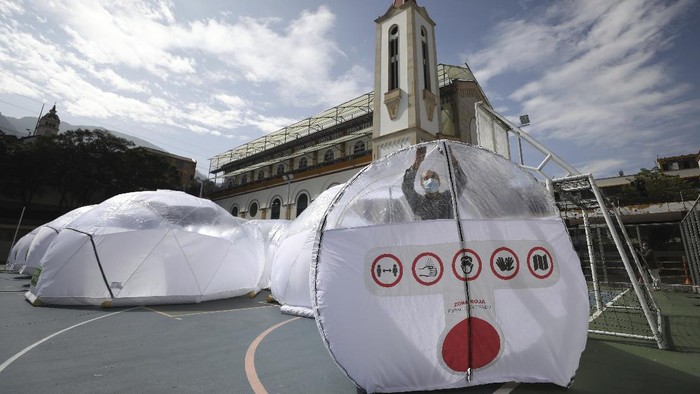 Designers stand inside a Portable Epidemiological Insulation Unit during a media presentation, in Bogota, Colombia, Tuesday, Feb. 16, 2021. Colombia’s La Salle University school of architecture designed the small polyhedral pneumatic geodesic domes which can be used to isolate and treat COVID-19 patients in areas where there are no nearby hospitals or where existing hospitals are overwhelmed with patients. (AP Photo/Fernando Vergara)
