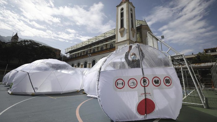 Kolombia Bakal Bikin Ruang Isolasi Pasien COVID-19 Portabel Designers stand inside a Portable Epidemiological Insulation Unit during a media presentation, in Bogota, Colombia, Tuesday, Feb. 16, 2021. Colombia’s La Salle University school of architecture designed the small polyhedral pneumatic geodesic domes which can be used to isolate and treat COVID-19 patients in areas where there are no nearby hospitals or where existing hospitals are overwhelmed with patients. (AP Photo/Fernando Vergara)