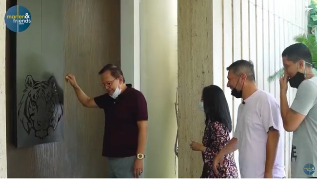 Kemegahan rumah bergaya minimalis kontemporer itu sudah terasa lewat pintu utama yang menyambut tamu. Pintu kayu berwarna coklat tua tersebut memiliki gagang yang dihiasi ukiran bermotif kepala harimau. (Foto: YouTube/Marten and Friends)