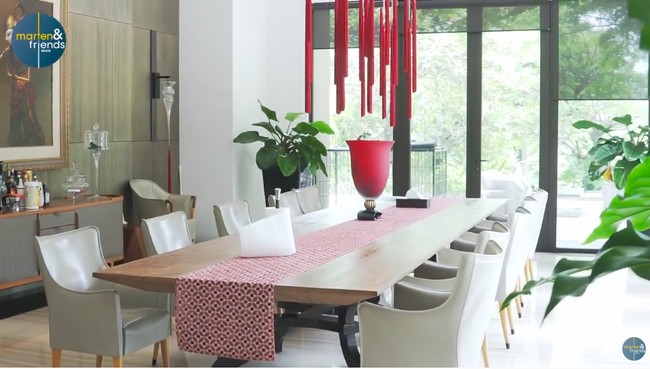 Ruang makan didesain khusus agar dapat menampung keluarga besar. Meja makan yang memanjang dihiasi runner bernuansa merah yang senada dengan vas dan lampu gantung. (Foto: YouTube/Marten and Friends)