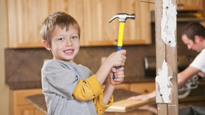 Young boy using a hammer to remodel a home.