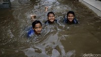 Sejumlah anak berenang di area sekitar rumah mereka yang terendam banjir di kawasan Tebet Barat, Jakarta, Kamis (18/2/2021).