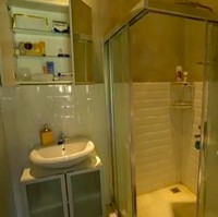 Inilah bagian kamar mandi yang dilengkapi sebuah pancuran dalam bilik kaca. Keramik putih meninggalkan kesan yang clean dan luas pada kamar mandi yang tak terlalu besar itu. (Foto: YouTube/Trans TV Official)