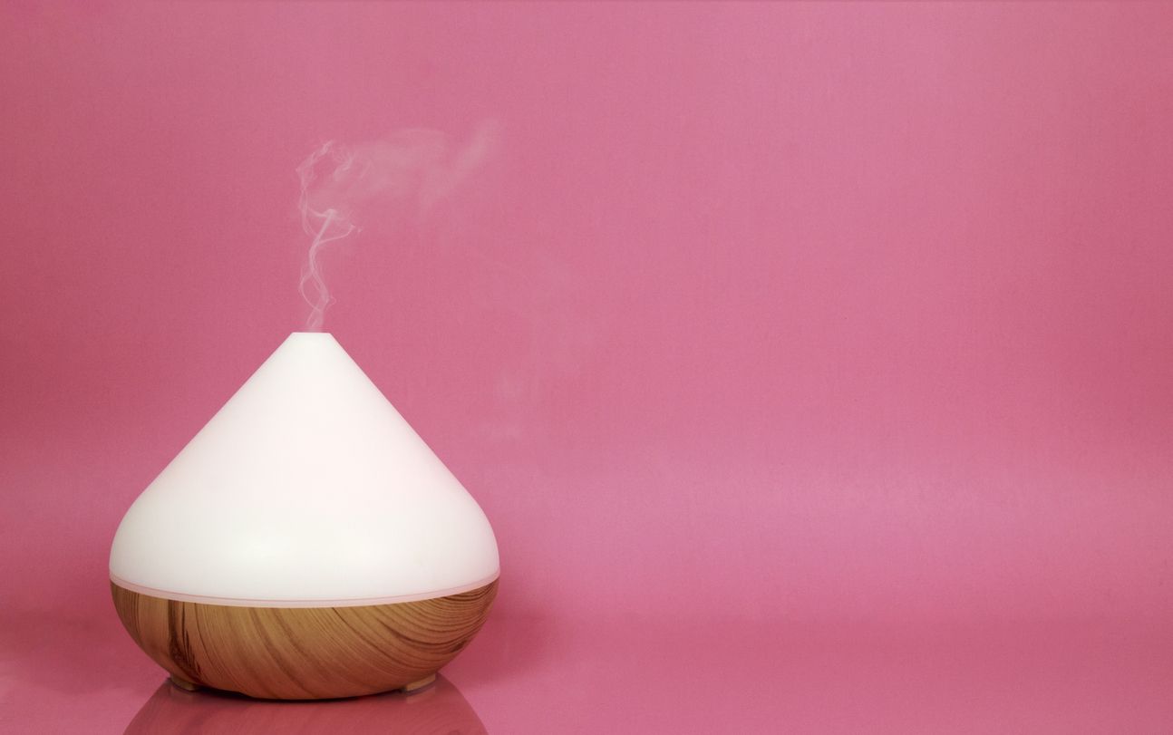 Electric essential oil diffuser isolated on pink background.