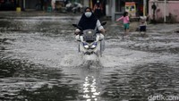 Pengendara sepeda motor menerobos banjir di Perumahan Taman Duta, Depok, Jawa Barat.