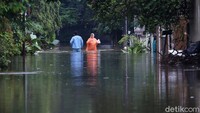 Warga melintasi banjir di Perumahan Jatibening Permai, Kota Bekasi, Jawa Barat, Jumat (19/2/2021).