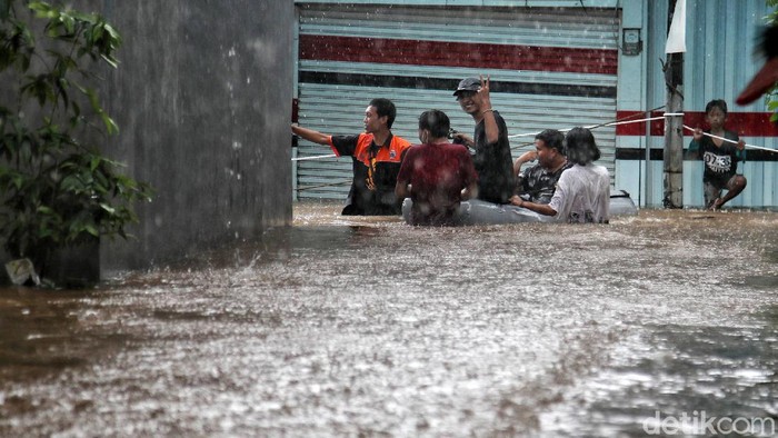 Sejumlah warga menerobos banjir di kawasan Kampung RW04 Cipinang Melayu, Jakarta Timur, Jumat (19/2). Saat ini banjir setinggi 1 meter lebih masih menggenangi kawasan banjir tersebut dan diprediksi jika hujan lagi maka akan lama surutnya