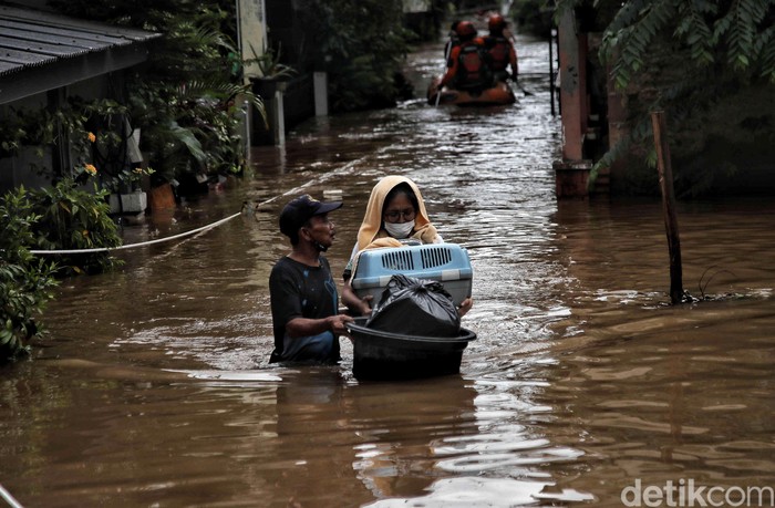 Sejumlah warga menerobos banjir di kawasan Kampung RW04 Cipinang Melayu, Jakarta Timur, Jumat (19/2). Saat ini banjir setinggi 1 meter lebih masih menggenangi kawasan banjir tersebut dan diprediksi jika hujan lagi maka akan lama surutnya
