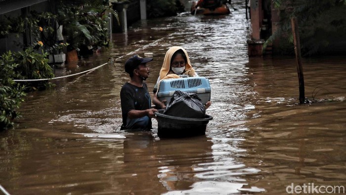 Sejumlah warga menerobos banjir di kawasan Kampung RW04 Cipinang Melayu, Jakarta Timur, Jumat (19/2). Saat ini banjir setinggi 1 meter lebih masih menggenangi kawasan banjir tersebut dan diprediksi jika hujan lagi maka akan lama surutnya