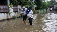 Seorang wanita hamil itu dievakuasi dengan cara dipapah melintasi genangan banjir.