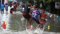 Sejumlah anak justru asyik bermain di tengah banjir.