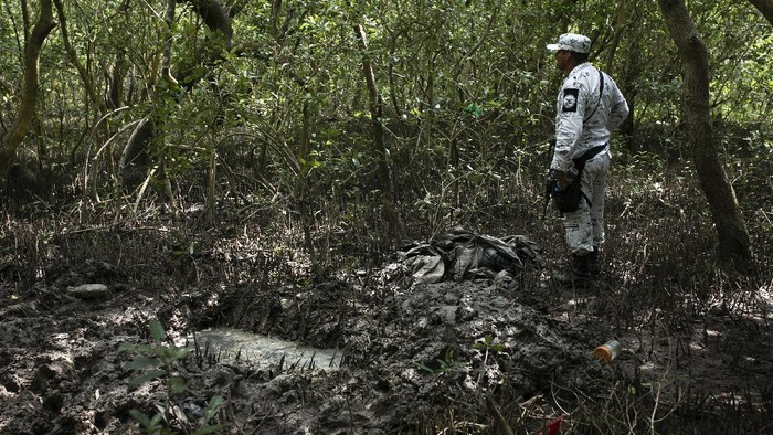 Penemuan Lubang Makam Rahasia di Meksiko Investigators from the National Search Commission take a boat in Puquita a tropical mangrove island, near Alvarado in the Gulf coast state of Veracruz, Mexico, where a clandestine grave site has been found, Thursday, Feb. 18, 2021. Investigators found three pits with human remains and plastic bags inside. The number of bodies there has not yet been determined. (AP Photo/Felix Marquez)