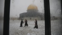 Beberapa jamaah berdoa di luar Kubah Batu atau Dome of The Rock yang sebagian tertutup salju.  AP/Oded Balilty