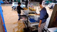 Dua orang pedagang gorengan, Rizal dan Robi tetap menggelar dagangannya meski Jalan Jatiasih-Pondok Gede tergenang banjir.