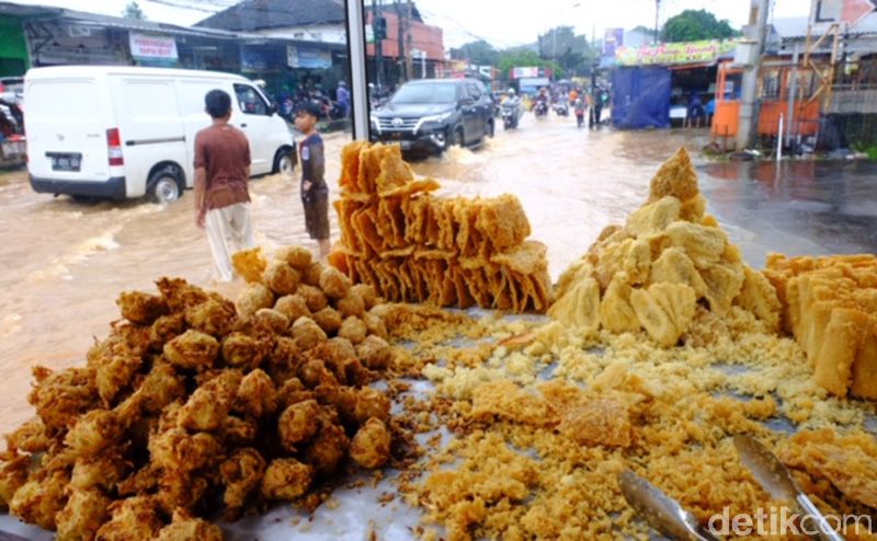 Hujan menyebabkan genangan di Jalan Jatiasih-Pondok Gede, Bekasi. Namun di tengah genangan itu, ada pedagang gorengan yang dengan santainya berjualan.