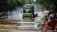 Kendaraan besak seperti truk nekat melintas di jalan yang terendam banjir.