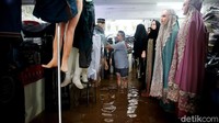 Seorang pedagang nekat berjualan meski kiosnya terendam banjir.