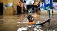 Tanpa rasa takut, anak tersebut asyik berenang di kawasan pasar yang terendam air.