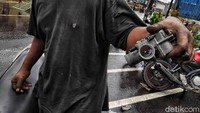 Mekanik dadakan menunjukkan karburator motor yang akan dibersihkan usai kemasukan air.