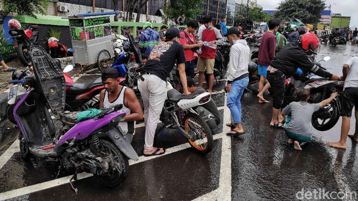 Sejumlah tukang bengkel keliling memperbaiki motor warga yang mati akibat menerobos banjir di kawasan Jalan Kapuk Raya, Penjaringan, Jakarta Utara, Sabtu (20/2). Jasa servis motor tersebut berkisar pada harga Rp. 25.000-Rp.100.000 tergantung tingkat kerusakan dan jasa bongkar mesin. Biasanya kebanyakan motor banjir rusak di busi dan karbu