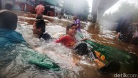 Mereka terlihat ceria bermain banjir di jalan tersebut.
