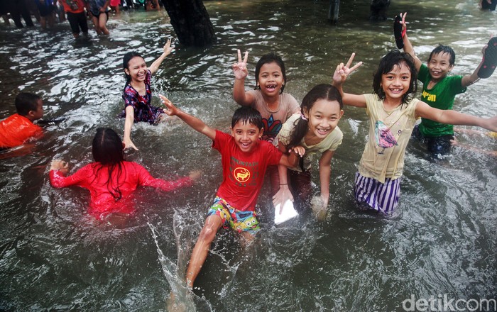 Keceriaan Anak-anak Bermain Banjir di Jalan Tendean Anak-anak bermain di banjir di Jl Kapten Tendean, Jakarta, Sabtu, (20/2/2021).