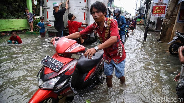 Sejumlah warga mendorong motornya yang mogok di kawasan yang terendam banjir, Kapuk Muara, Penjaringan, Jakarta Utara, Sabtu (20/2). Banyak motor warga yang mogok akibat nekat menerobos banjir setinggi 70 cm itu.