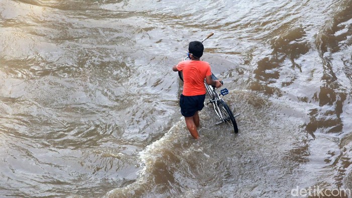 Pesepeda melintasi banjir di Jl Tendean, Sabtu, (20/2/2021). Sepeda tanpa mesin ini dijamin tidak mogok melewati ketinggian air.