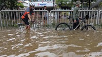 Banjir memutus arus lalu lintas di jalan tersebut. Motor dan mobil tak berani melintas, hanya pesepeda yang nekat menerobos banjir.