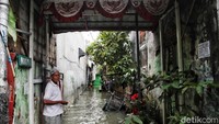 Warga berjaga di depan gang sambil menunggu banjir surut.