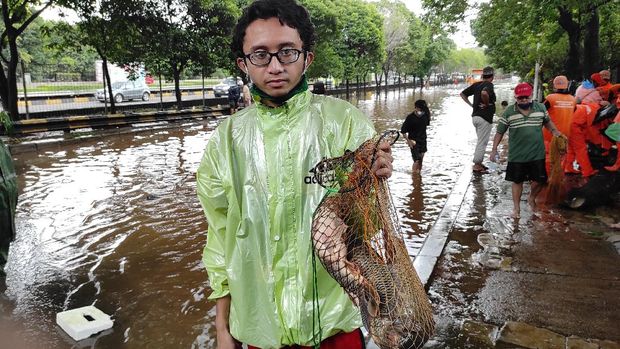 Warga sekitar Kementan menjaring ikan saat terjadi banjir.